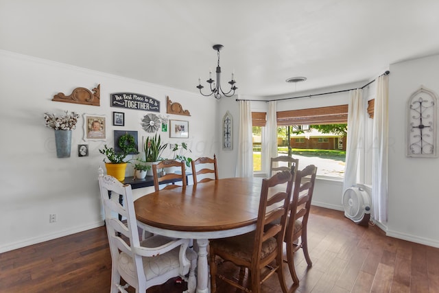 dining area featuring dark wood-type flooring, a chandelier, and crown molding