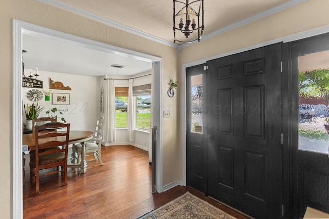 foyer with a chandelier, dark hardwood / wood-style floors, and crown molding