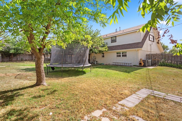 view of yard with central AC unit and a trampoline