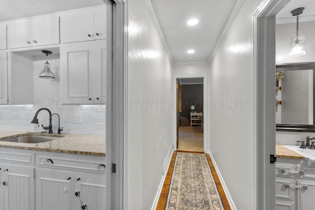 interior space with wood-type flooring, vanity, backsplash, and crown molding