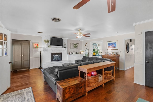 living room with dark wood-type flooring, ornamental molding, and a fireplace