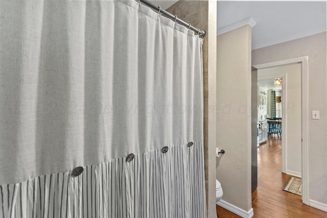 bathroom featuring hardwood / wood-style flooring, curtained shower, toilet, and ornamental molding