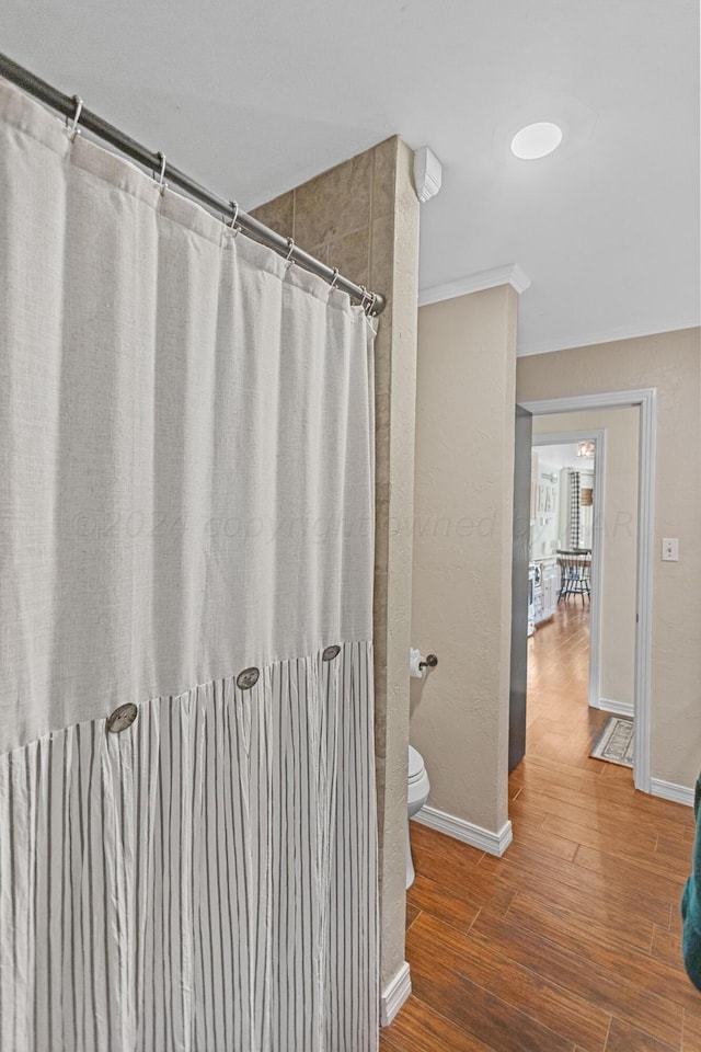 bathroom featuring hardwood / wood-style floors, curtained shower, toilet, and crown molding