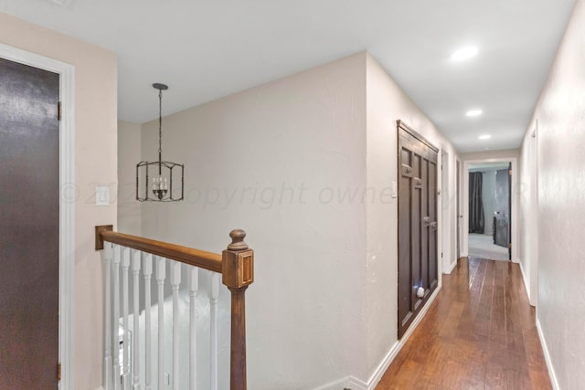 corridor featuring wood-type flooring and a notable chandelier