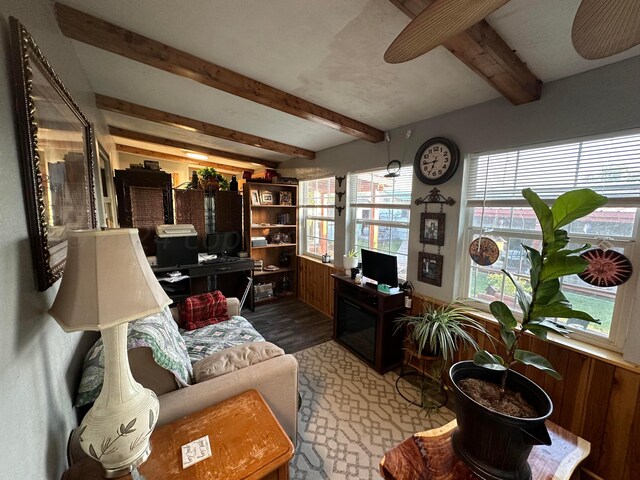 living room featuring wood walls, hardwood / wood-style flooring, plenty of natural light, and beam ceiling