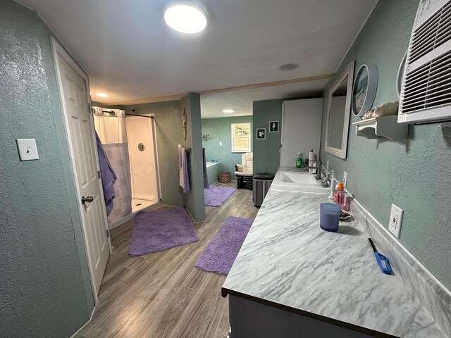 bathroom featuring a wall unit AC, wood-type flooring, vanity, and shower with separate bathtub