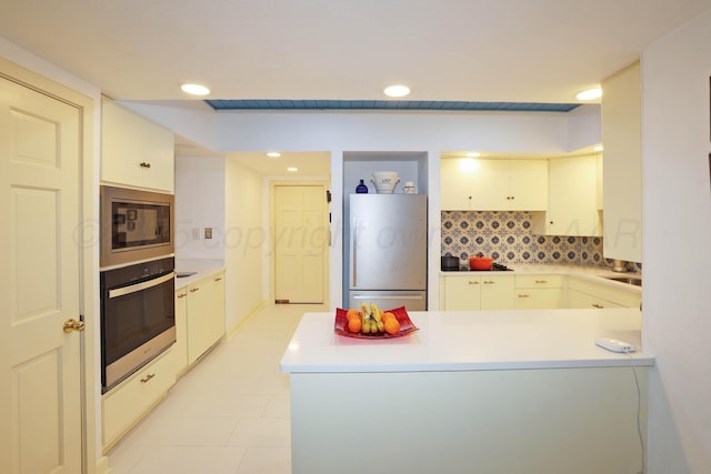 kitchen featuring tasteful backsplash, stainless steel appliances, kitchen peninsula, and white cabinets