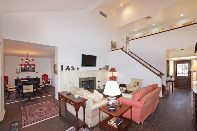 living room with a tile fireplace, dark hardwood / wood-style floors, high vaulted ceiling, beamed ceiling, and a chandelier