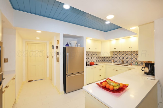 kitchen with sink, wooden ceiling, stainless steel refrigerator, kitchen peninsula, and backsplash