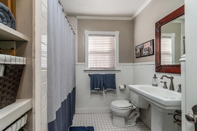 bathroom featuring ornamental molding, tile patterned flooring, wainscoting, and toilet