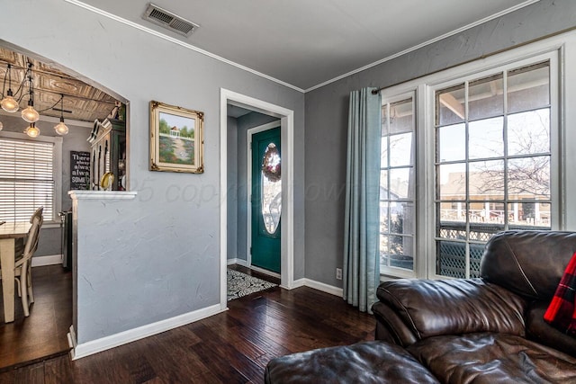 foyer entrance with ornamental molding, dark wood-type flooring, visible vents, and baseboards