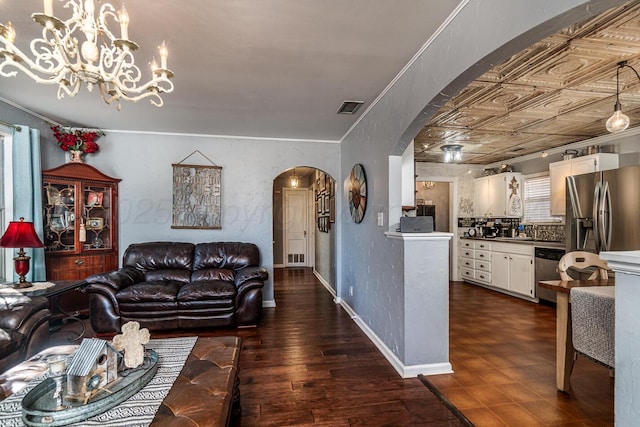 living area featuring visible vents, arched walkways, dark wood finished floors, baseboards, and an ornate ceiling