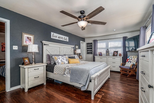 bedroom with a textured wall, dark wood finished floors, baseboards, and a ceiling fan