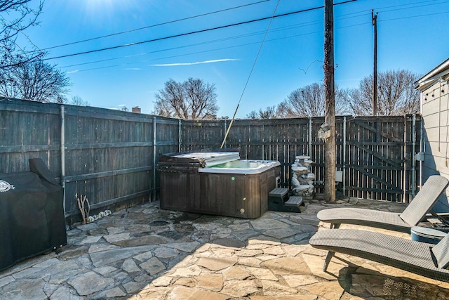 view of patio / terrace with a fenced backyard, a hot tub, and grilling area