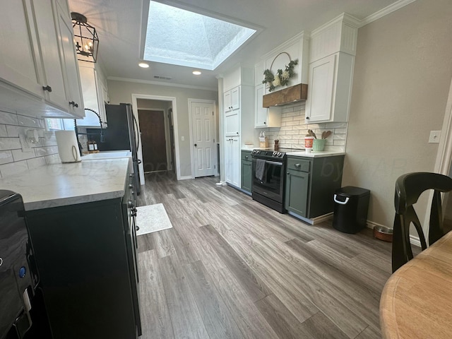 313 Mustang St, Fritch, TX 79036 - kitchen featuring black / electric stove, crown molding, light countertops, a skylight, and light wood finished floors