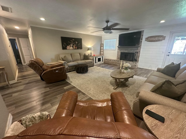 313 Mustang St, Fritch, TX 79036 - living area featuring a ceiling fan, dark wood-style flooring, a fireplace with raised hearth, plenty of natural light, and ornamental molding