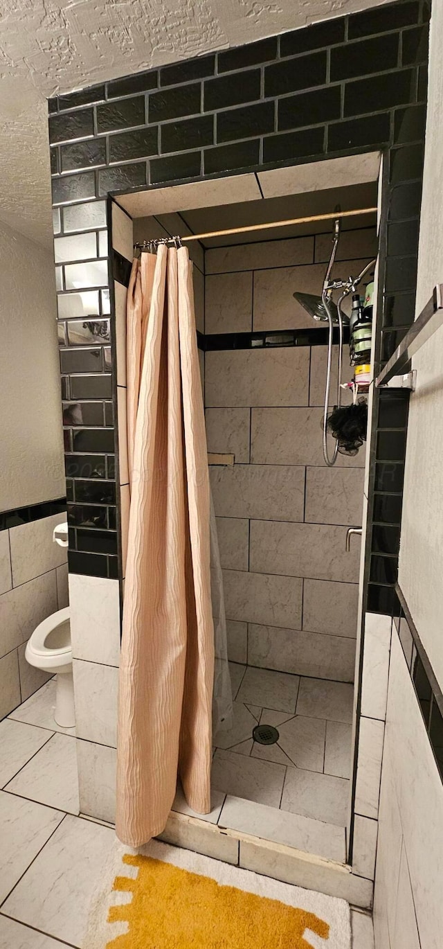 bathroom with tile walls, a shower with curtain, and toilet