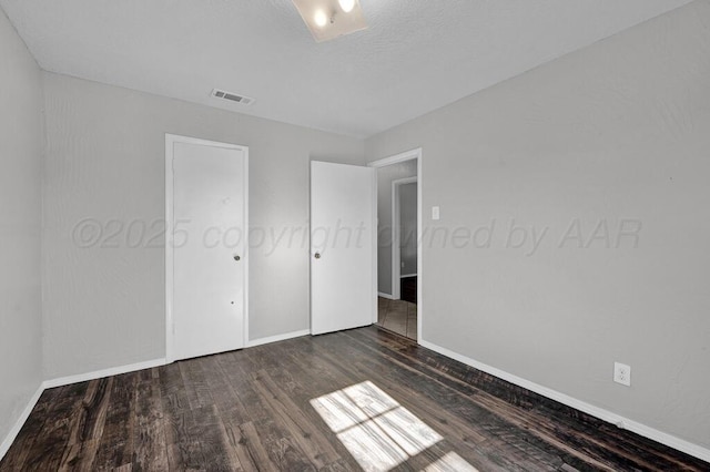 unfurnished bedroom with baseboards, wood finished floors, and visible vents