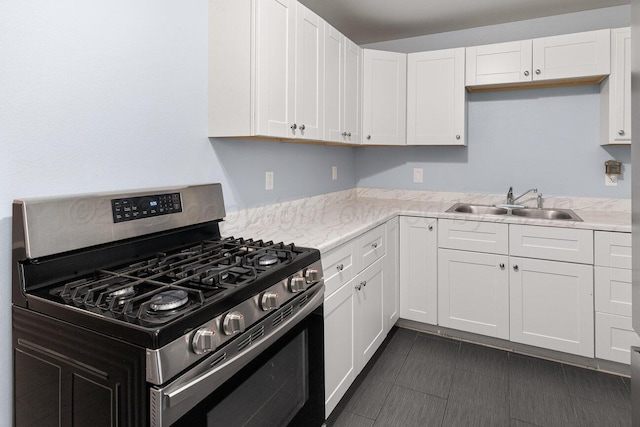 3804 NE 26th Ave, Amarillo, TX 79107 - kitchen with stainless steel gas range oven, a sink, white cabinets, and light stone countertops
