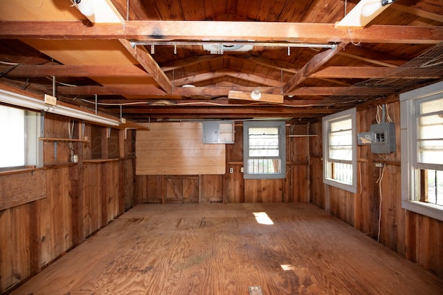 misc room with a healthy amount of sunlight, electric panel, and wooden walls