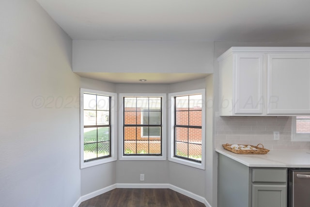unfurnished dining area featuring baseboards, a wealth of natural light, and dark wood-type flooring
