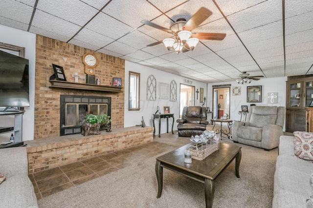 tiled living room with a fireplace and ceiling fan