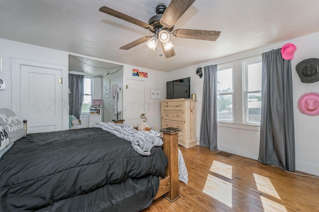 bedroom featuring ceiling fan, multiple windows, and light hardwood / wood-style flooring