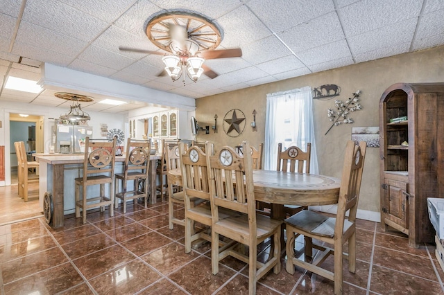 tiled dining room with ceiling fan and a drop ceiling