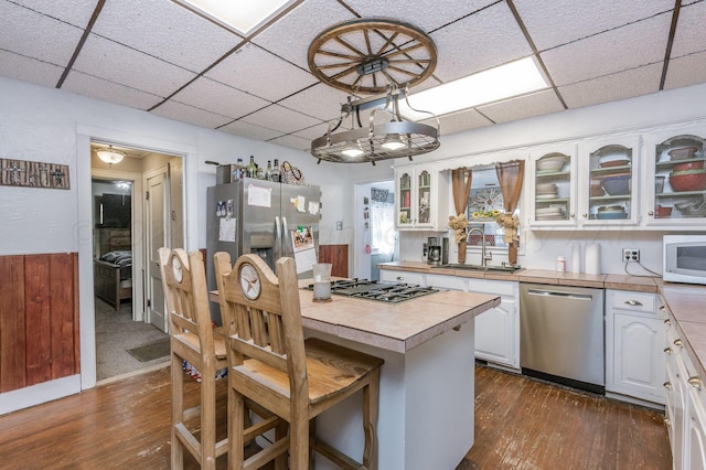 kitchen featuring tile counters, white cabinets, a paneled ceiling, dark hardwood / wood-style floors, and appliances with stainless steel finishes