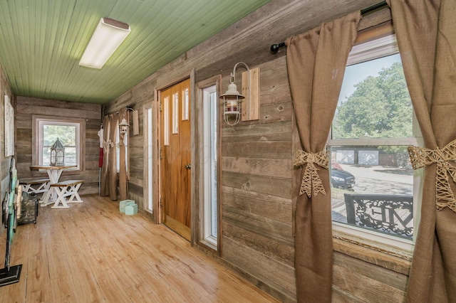 misc room featuring light hardwood / wood-style flooring, wood walls, and wooden ceiling