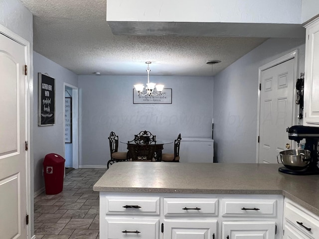 kitchen with white cabinets, a textured ceiling, decorative light fixtures, and kitchen peninsula