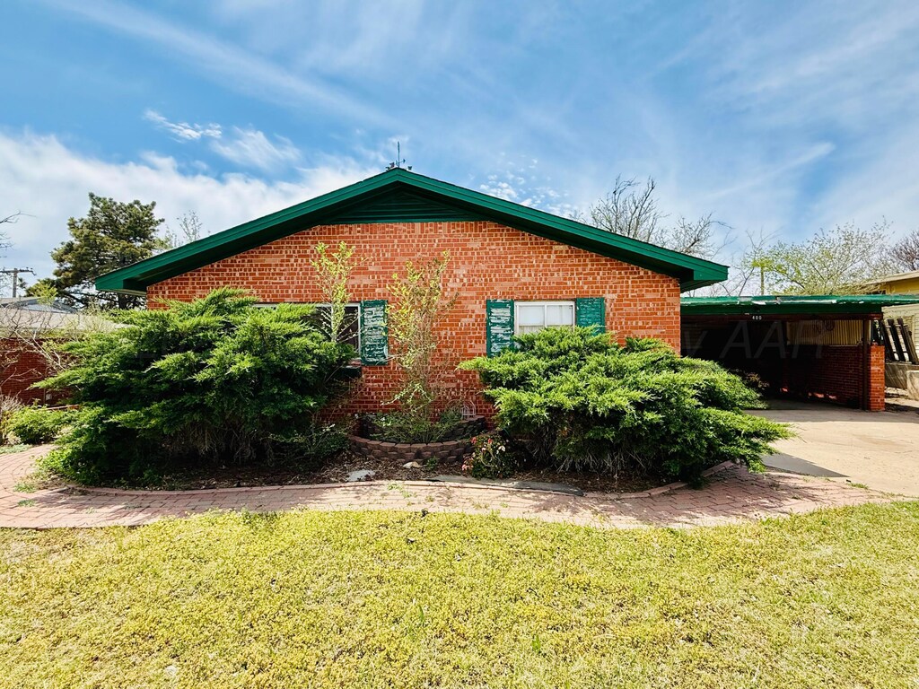 400 Santa Fe St, Borger, TX 79007 - view of home's exterior with brick siding, driveway, an attached carport, and a lawn