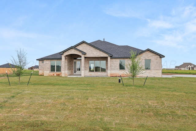 view of front of house featuring brick siding, a front lawn, and roof with shingles