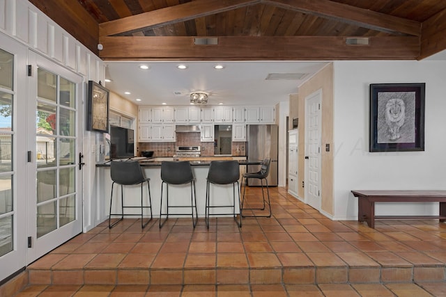 3408 Carlton Dr, Amarillo, TX 79109 - kitchen featuring freestanding refrigerator, a peninsula, wooden ceiling, decorative backsplash, and white cabinetry