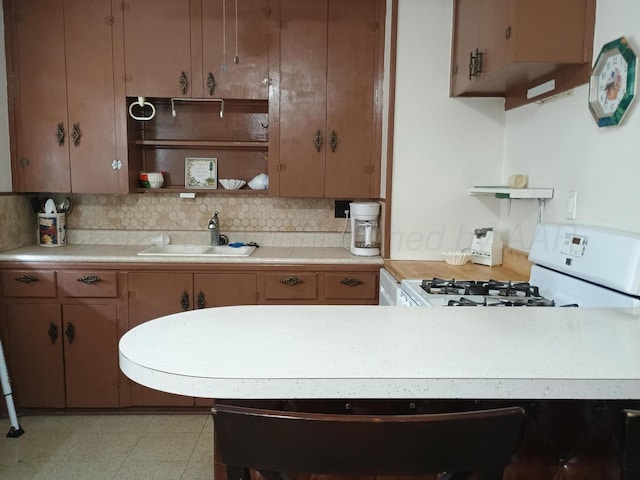 kitchen featuring gas range gas stove, decorative backsplash, sink, and light tile patterned flooring