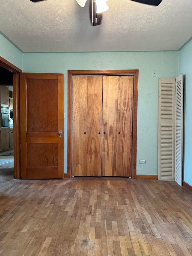 unfurnished bedroom with hardwood / wood-style floors, ceiling fan, and a textured ceiling