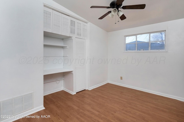 unfurnished bedroom with a ceiling fan, visible vents, wood finished floors, baseboards, and a closet
