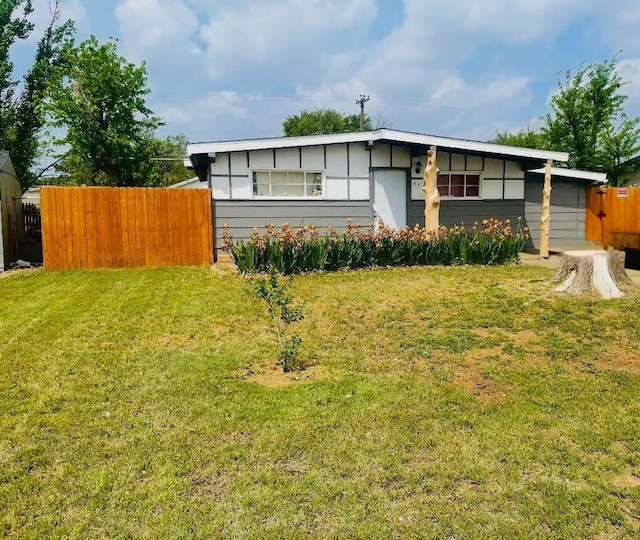 view of front of home featuring fence and a front lawn
