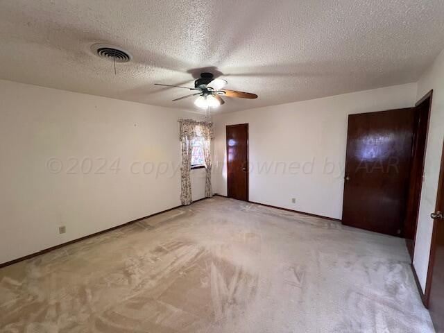 carpeted empty room with a textured ceiling and ceiling fan