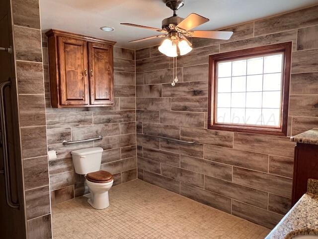 bathroom featuring toilet, vanity, a tile shower, and ceiling fan