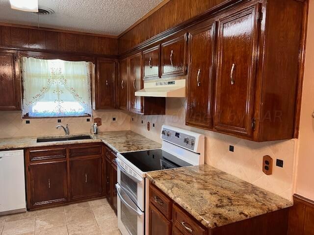 kitchen featuring light stone counters, a textured ceiling, sink, backsplash, and white appliances