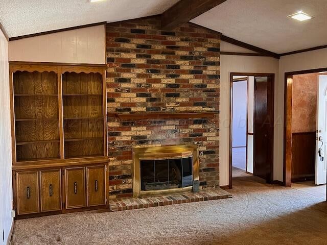 unfurnished living room featuring a textured ceiling, carpet flooring, a fireplace, crown molding, and lofted ceiling with beams