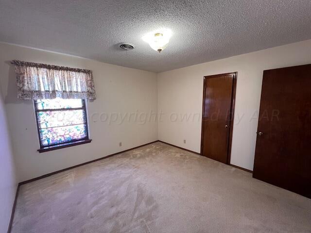 unfurnished room with a textured ceiling and carpet flooring