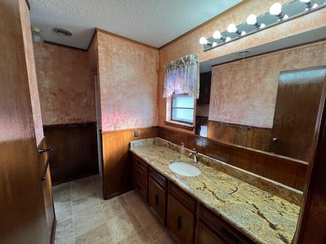 bathroom featuring vanity, wooden walls, and a textured ceiling