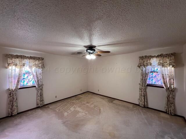 carpeted empty room featuring ceiling fan, plenty of natural light, and a textured ceiling