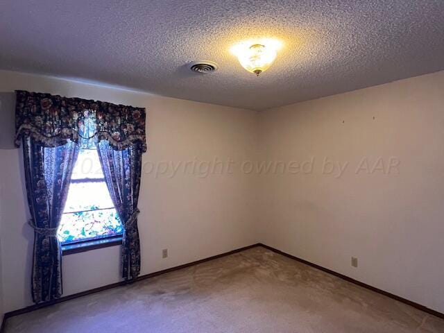 carpeted empty room with a textured ceiling