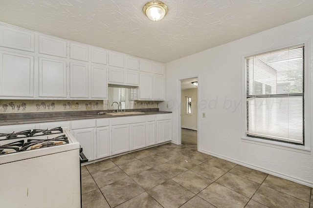 4004 S Van Buren St, Amarillo, TX 79110 - kitchen with white gas range, white cabinetry, light tile patterned floors, and dark countertops