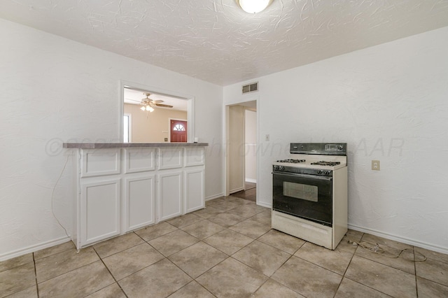 4004 S Van Buren St, Amarillo, TX 79110 - kitchen with white range with gas cooktop, white cabinetry, light tile patterned flooring, and a textured ceiling