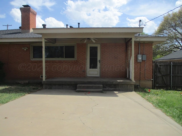 rear view of house featuring brick siding, ceiling fan, and a chimney