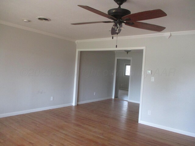 empty room featuring crown molding, wood finished floors, a ceiling fan, and baseboards
